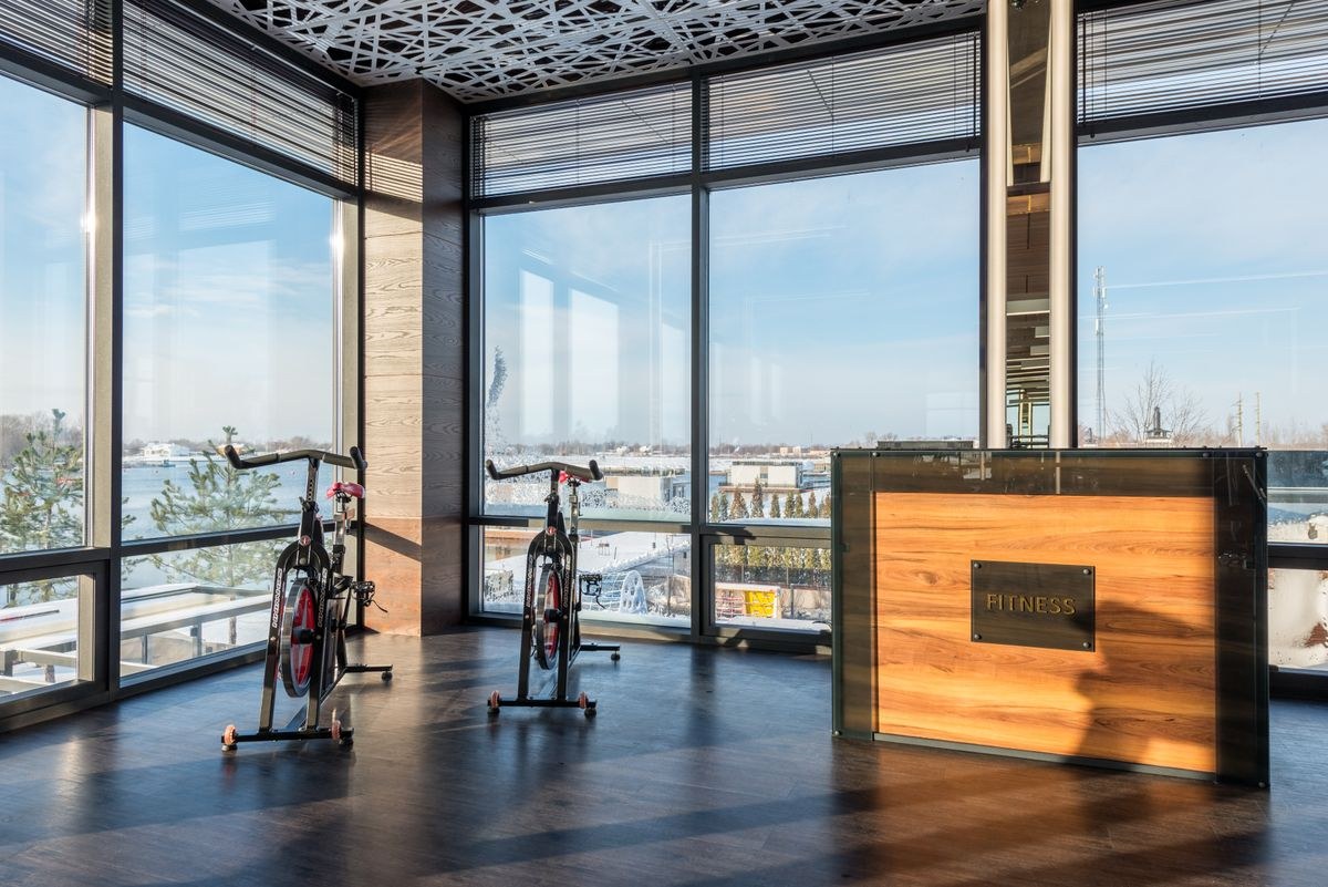 Two black spin bikes by floor-to-ceiling windows in a bright fitness room